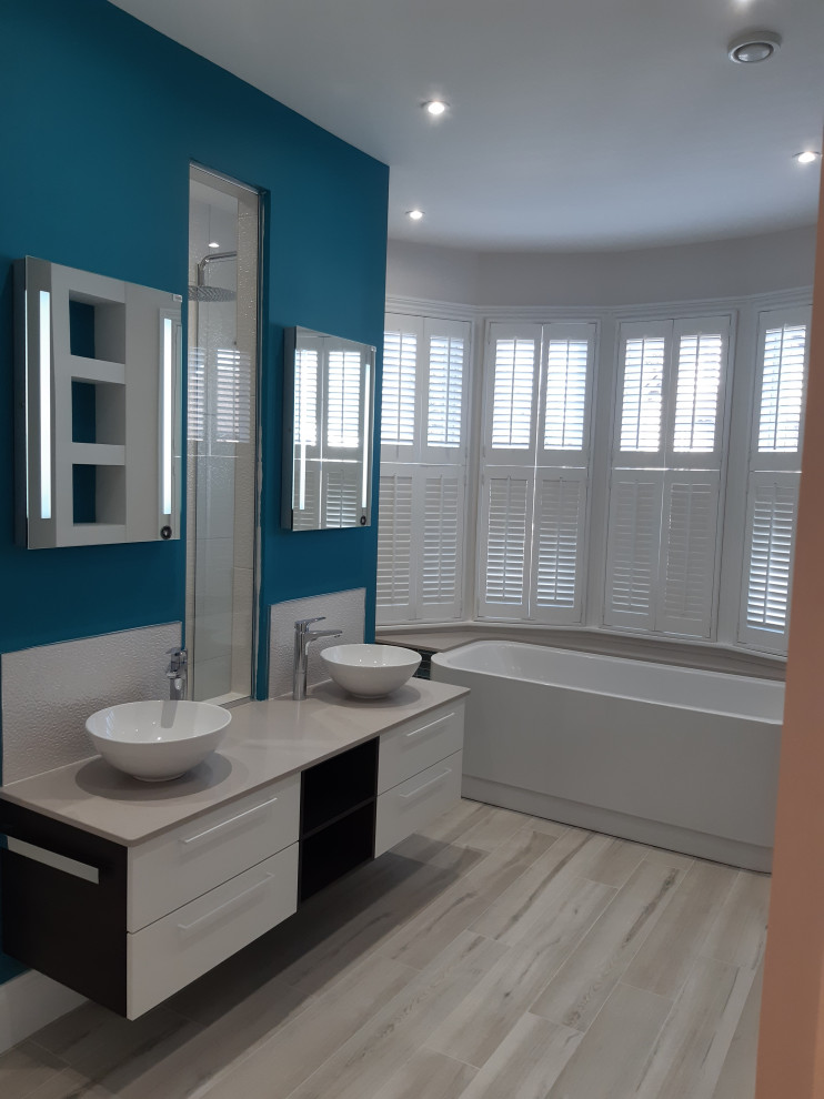 Foto på ett stort funkis vit en-suite badrum, med släta luckor, vita skåp, ett platsbyggt badkar, en öppen dusch, en vägghängd toalettstol, bänkskiva i kvartsit, grått golv och med dusch som är öppen