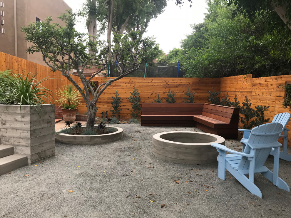 This is an example of a small modern backyard partial sun xeriscape for winter in San Diego with a fire feature and gravel.