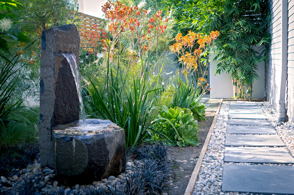 Photo of a small contemporary backyard xeriscape in Los Angeles with a water feature and river rock.