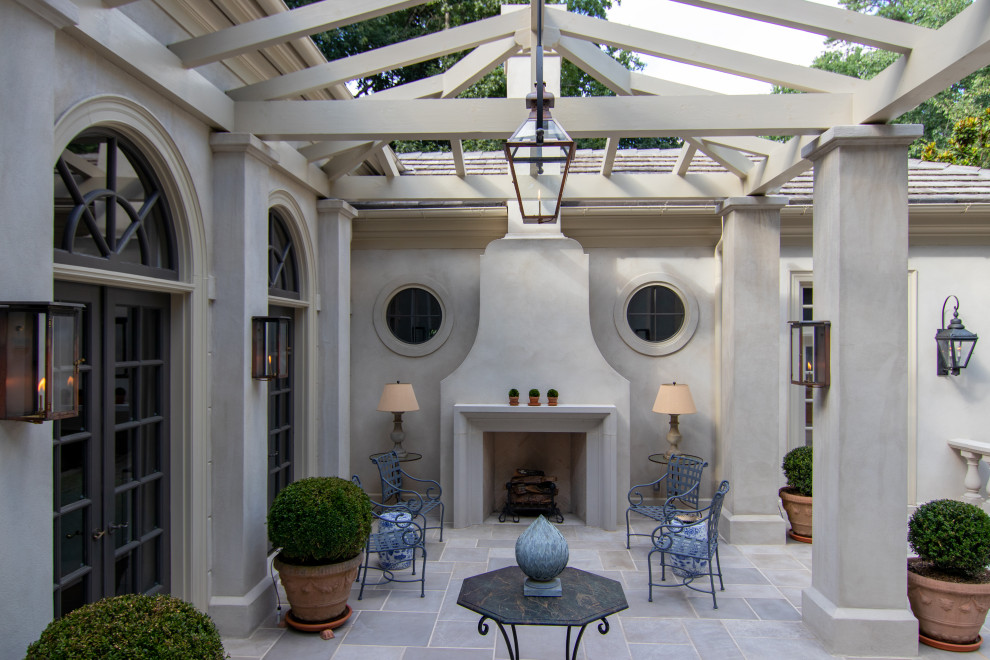 This is an example of a large courtyard patio in Denver with with fireplace, natural stone pavers and a pergola.