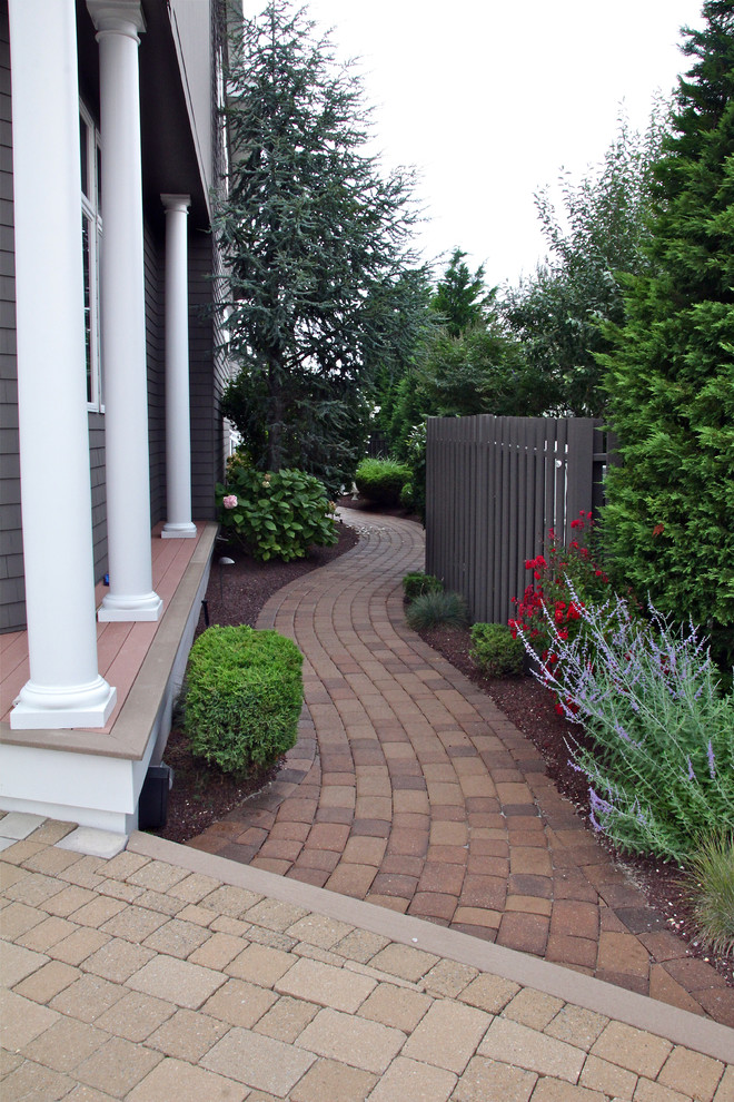 This is an example of a traditional side yard garden in New York with a garden path and brick pavers.