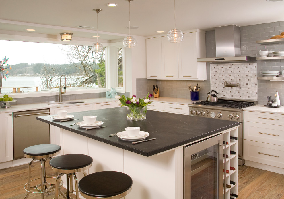 Inspiration for a mid-sized transitional l-shaped eat-in kitchen in Seattle with an undermount sink, white cabinets, soapstone benchtops, shaker cabinets, medium hardwood floors, with island, multi-coloured splashback, mosaic tile splashback, panelled appliances and brown floor.