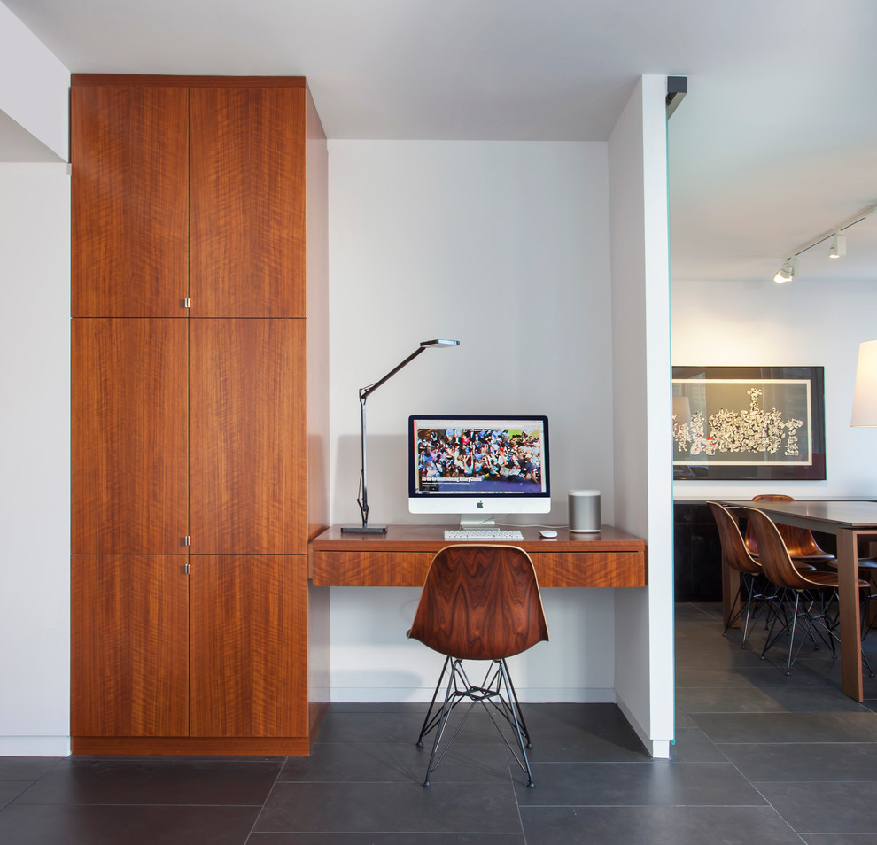 This is an example of a mid-sized contemporary home office in Chicago with white walls, porcelain floors, no fireplace, a built-in desk and grey floor.