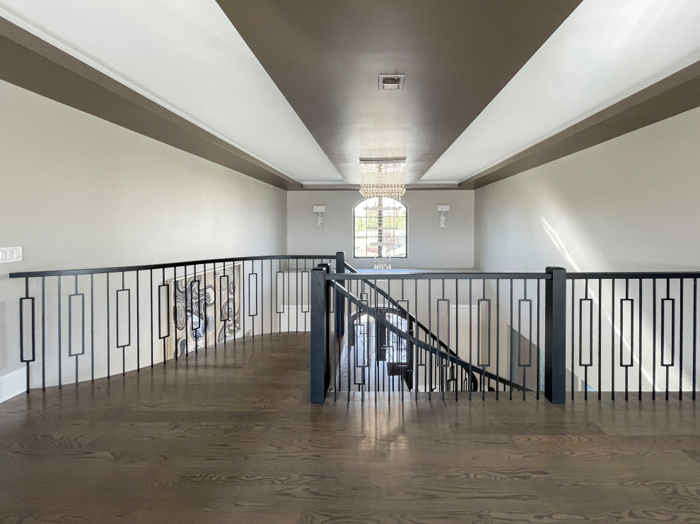 Diseño de escalera curva clásica renovada extra grande con escalones de madera, contrahuellas de madera pintada, barandilla de varios materiales y papel pintado
