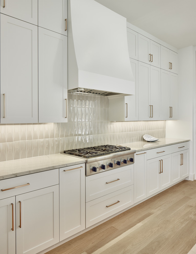 Inspiration for a large traditional l-shaped open plan kitchen in Dallas with recessed-panel cabinets, white cabinets, quartz worktops, grey splashback, ceramic splashback, light hardwood flooring and an island.