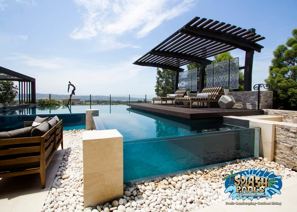 Photo of a mid-sized modern backyard custom-shaped infinity pool in Orange County with a water feature and tile.