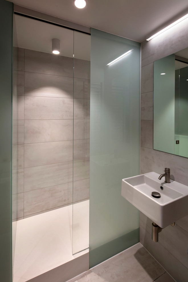 Photo of a small contemporary 3/4 bathroom in London with glass-front cabinets, white cabinets, a curbless shower, white tile, ceramic tile, white walls, ceramic floors, a wall-mount sink and solid surface benchtops.