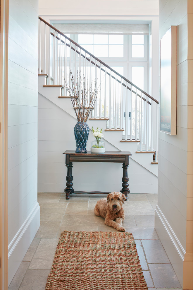 Mid-sized beach style hallway in Charleston with white walls and limestone floors.