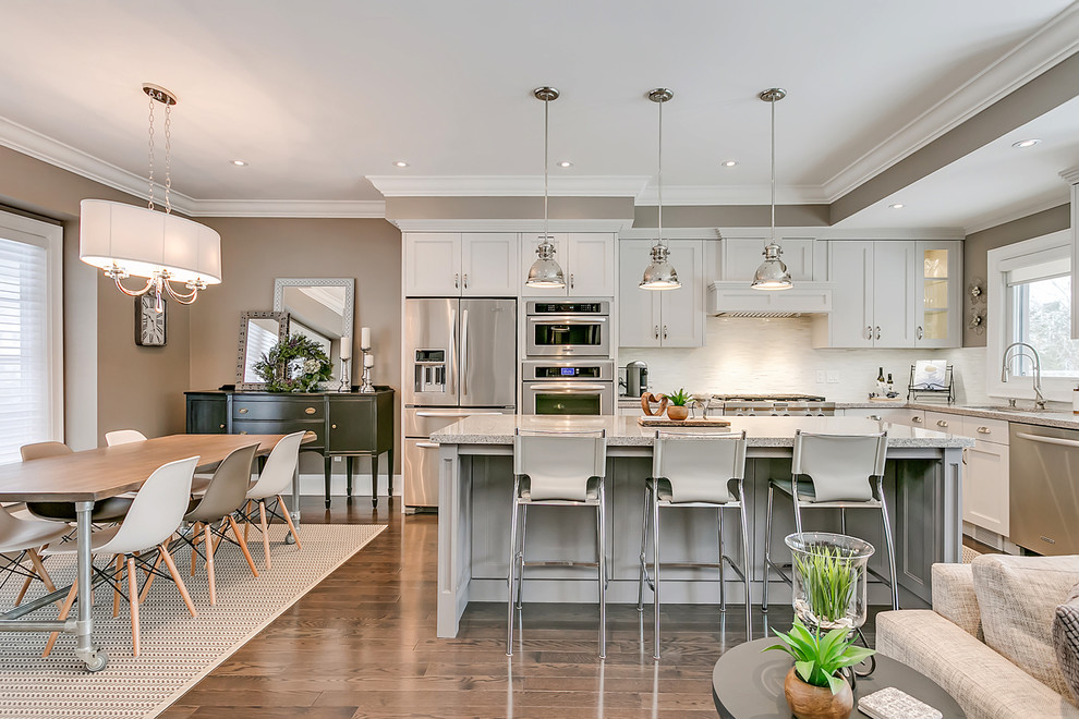 Example of a mid-sized transitional l-shaped open concept kitchen design in Toronto with an undermount sink, shaker cabinets, white cabinets, quartz countertops, white backsplash, matchstick tile backsplash, stainless steel appliances, an island and multicolored countertops