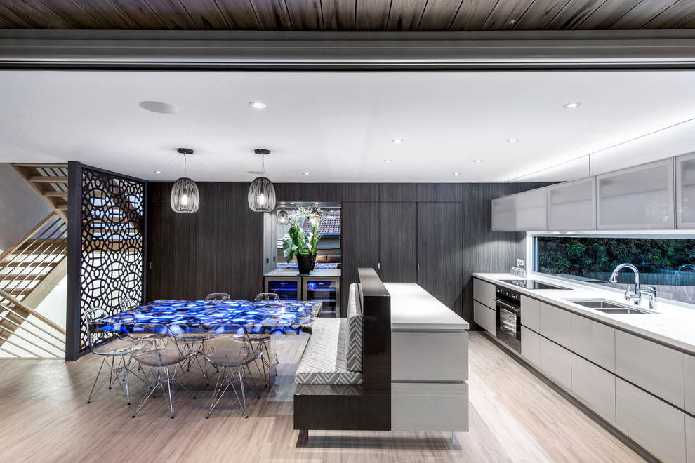 Photo of a large contemporary galley eat-in kitchen in Brisbane with an undermount sink, flat-panel cabinets, beige cabinets, quartz benchtops, glass sheet splashback, white appliances, laminate floors and with island.