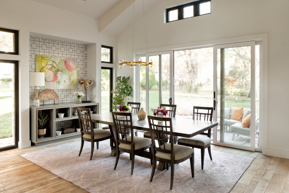 Photo of a traditional open plan dining room in Kansas City with white walls, light hardwood flooring, no fireplace, beige floors and a vaulted ceiling.