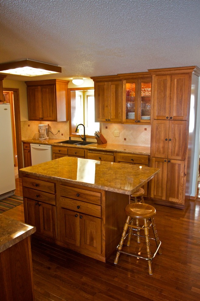 Mid-sized u-shaped eat-in kitchen photo with raised-panel cabinets, medium tone wood cabinets, laminate countertops, beige backsplash, stone tile backsplash, white appliances and an island