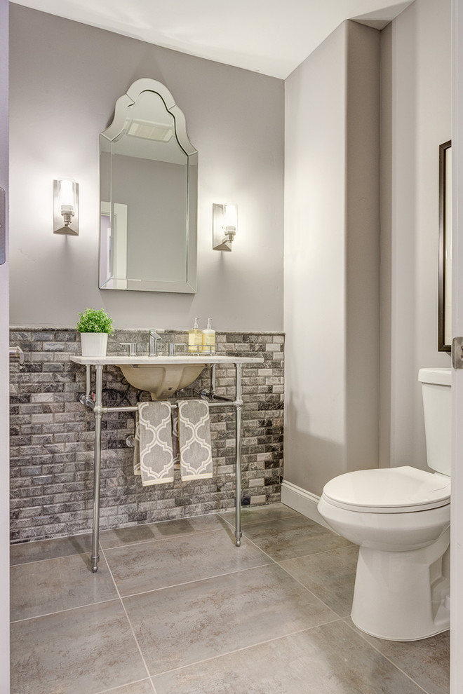 Inspiration for a mid-sized transitional powder room in Sacramento with solid surface benchtops, a one-piece toilet, gray tile, grey walls, porcelain floors, a console sink and stone tile.