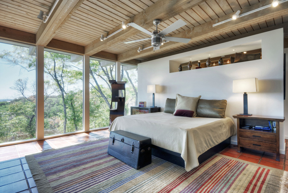 This is an example of a mid-sized contemporary master bedroom in Denver with white walls and terra-cotta floors.