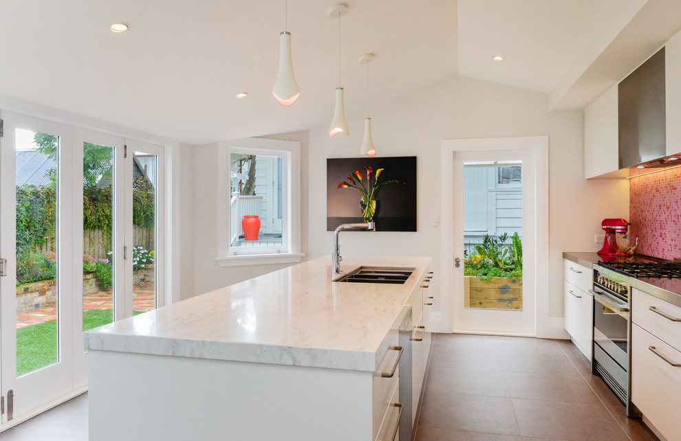 Inspiration for a small contemporary galley kitchen in Auckland with an undermount sink, flat-panel cabinets, white cabinets, solid surface benchtops, pink splashback, mosaic tile splashback, stainless steel appliances, ceramic floors and with island.