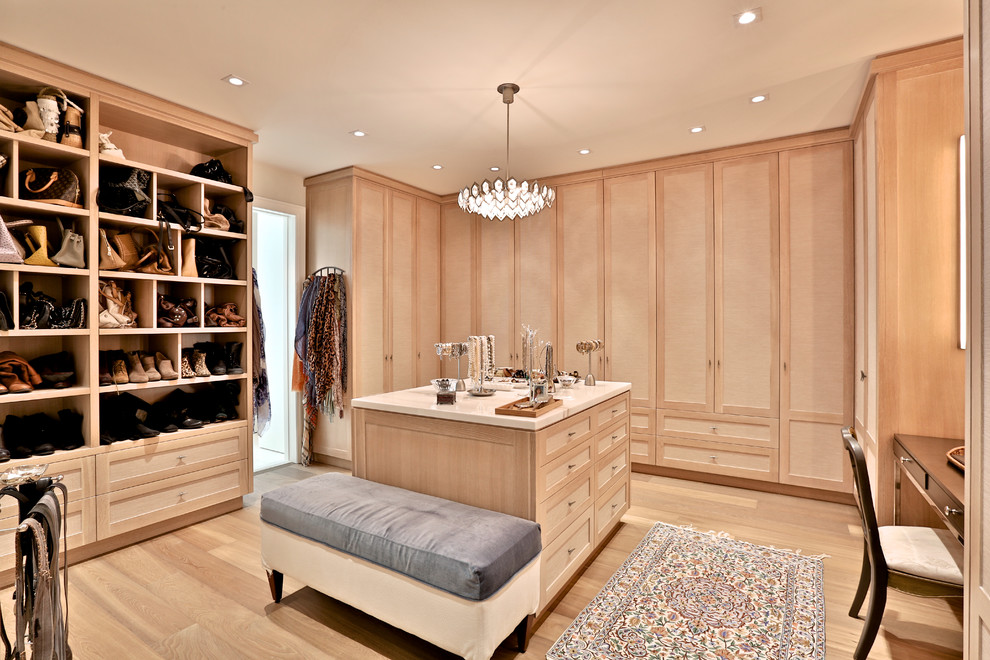 Photo of an expansive transitional gender-neutral dressing room in Toronto with light wood cabinets and light hardwood floors.