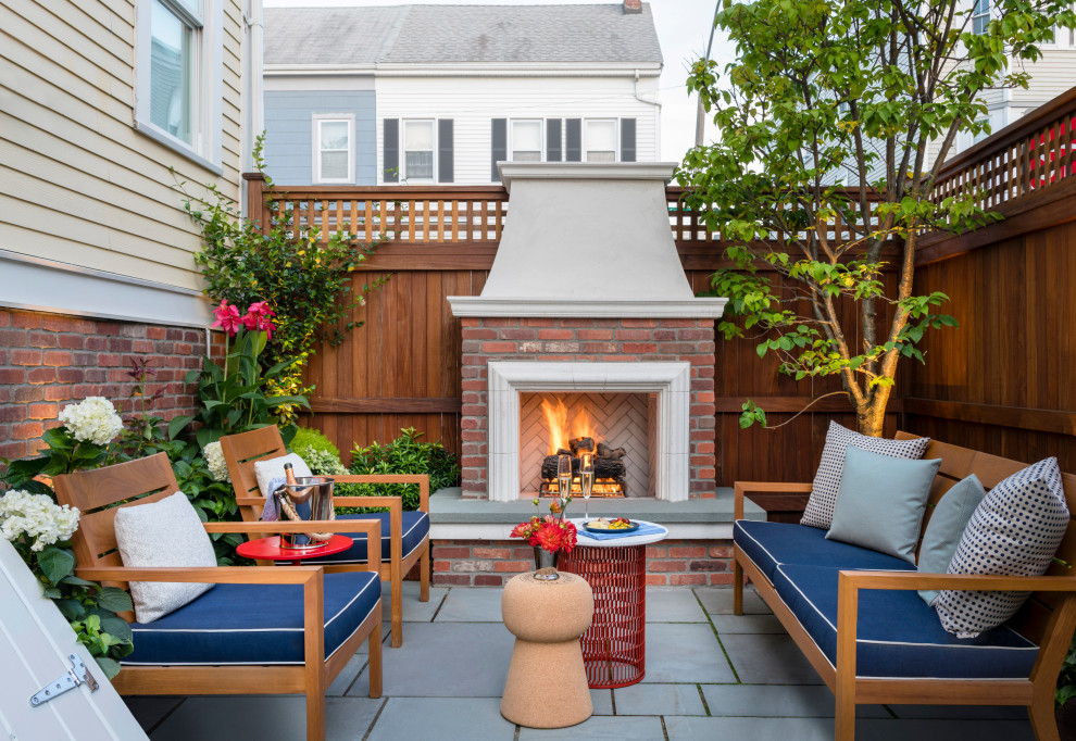 Patio - mid-sized transitional side yard stone patio idea in Boston with a fireplace and no cover