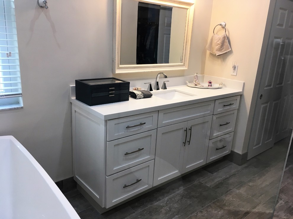 Inspiration for a mid-sized transitional master bathroom in Miami with shaker cabinets, white cabinets, a freestanding tub, an alcove shower, a two-piece toilet, gray tile, porcelain tile, beige walls, dark hardwood floors, an undermount sink and solid surface benchtops.