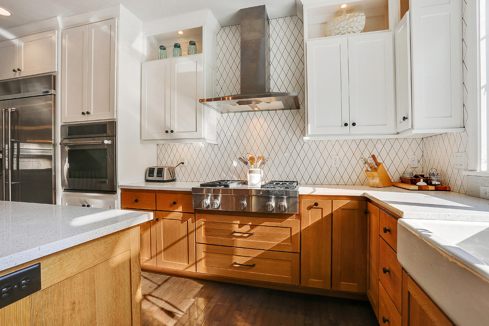 This is an example of a transitional kitchen in Other with a farmhouse sink, shaker cabinets, medium wood cabinets, white splashback, stainless steel appliances and dark hardwood floors.