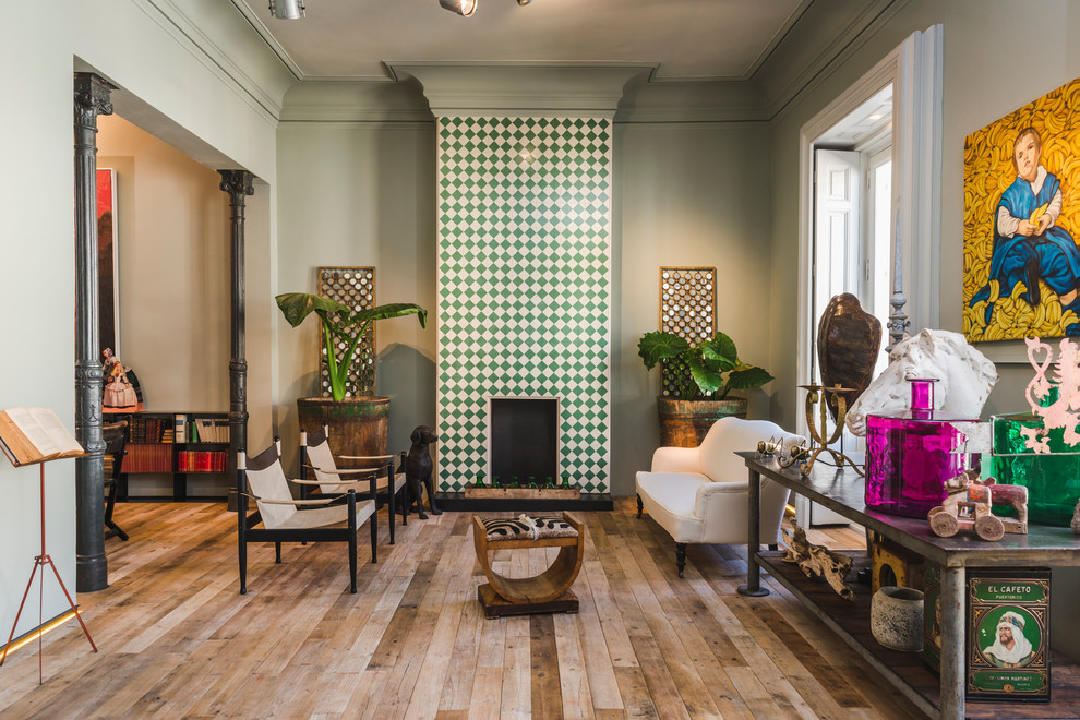 This is an example of a mid-sized eclectic formal open concept living room in Madrid with green walls, medium hardwood floors, a standard fireplace and no tv.