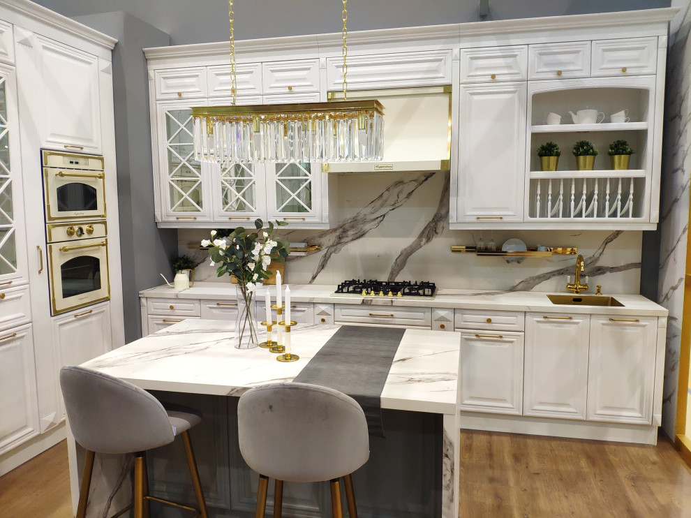 Inredning av ett klassiskt stort flerfärgad flerfärgat kök, med en undermonterad diskho, luckor med upphöjd panel, vita skåp, marmorbänkskiva, flerfärgad stänkskydd, stänkskydd i marmor, vita vitvaror, mellanmörkt trägolv, en köksö och brunt golv