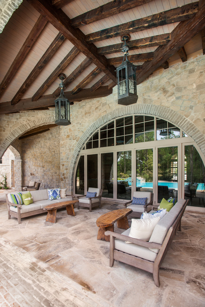 This is an example of an expansive mediterranean backyard patio in Houston with natural stone pavers and a roof extension.