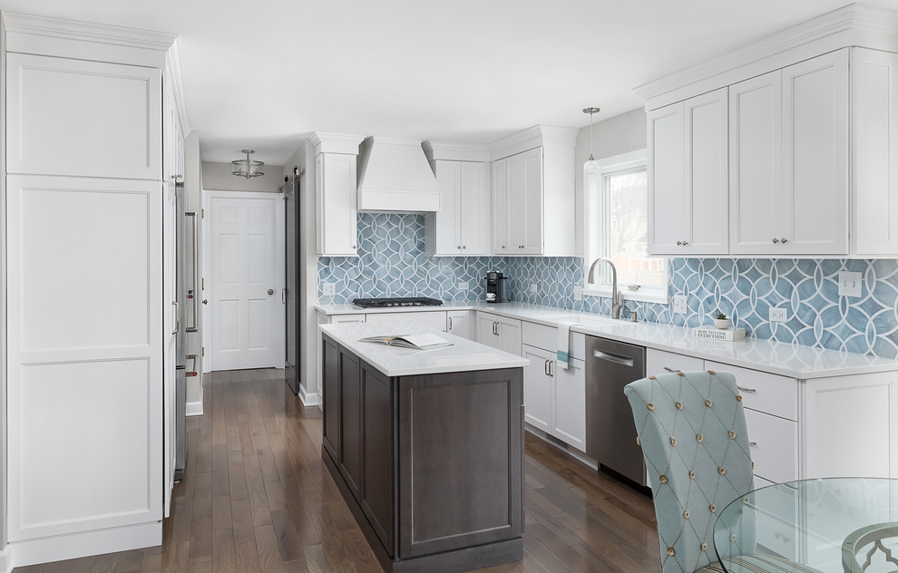 Photo of a mid-sized transitional u-shaped eat-in kitchen in Chicago with an undermount sink, recessed-panel cabinets, white cabinets, quartz benchtops, blue splashback, ceramic splashback, stainless steel appliances, dark hardwood floors, with island, brown floor and white benchtop.