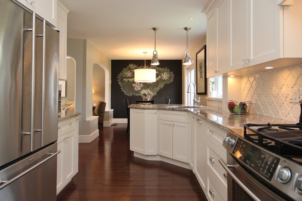 Example of a mid-sized transitional galley medium tone wood floor kitchen design in Ottawa with an undermount sink, shaker cabinets, white cabinets, granite countertops, white backsplash, ceramic backsplash and stainless steel appliances