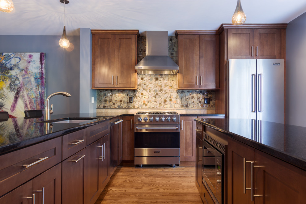 Photo of a mid-sized transitional l-shaped separate kitchen in Chicago with a double-bowl sink, shaker cabinets, medium wood cabinets, multi-coloured splashback, mosaic tile splashback, stainless steel appliances, medium hardwood floors, with island, granite benchtops, blue floor and brown benchtop.