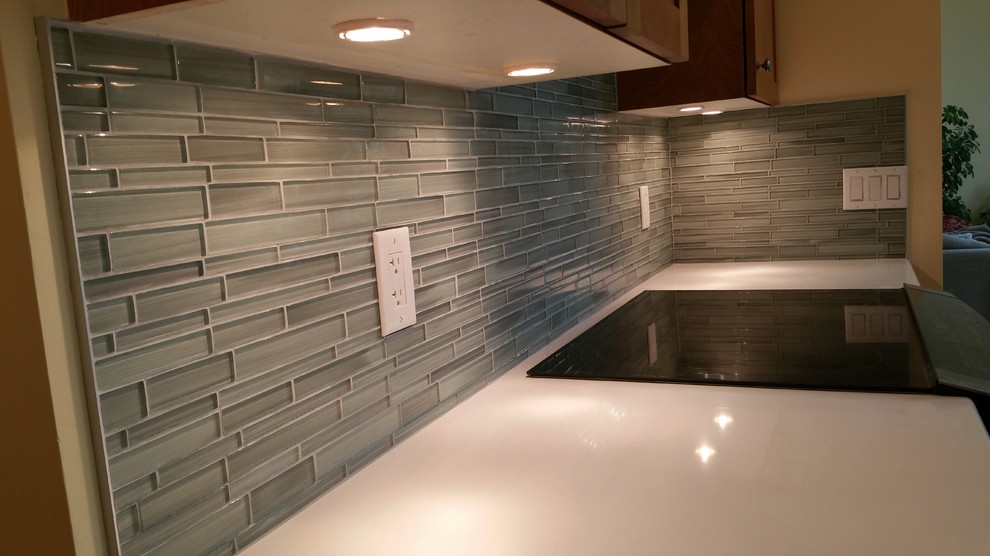 Inspiration for a large ceramic tile kitchen remodel in Ottawa with an undermount sink, recessed-panel cabinets, dark wood cabinets, quartz countertops, gray backsplash, glass sheet backsplash, stainless steel appliances and an island