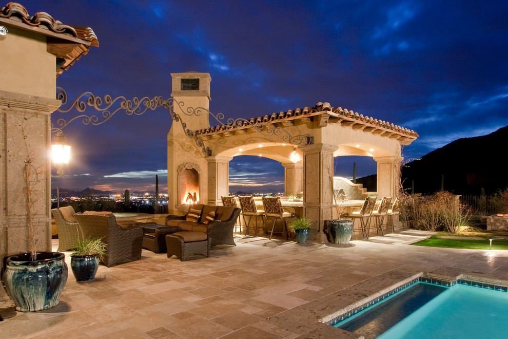 This is an example of an expansive traditional backyard patio in Phoenix with an outdoor kitchen, natural stone pavers and a gazebo/cabana.