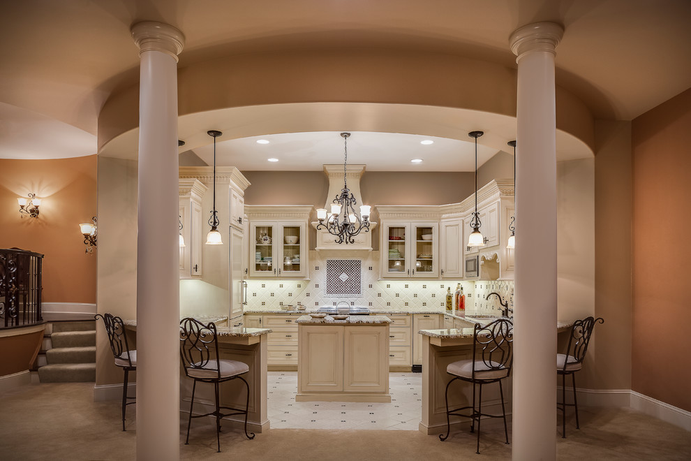 Inspiration for a large mediterranean u-shaped open plan kitchen in Kansas City with granite benchtops, beige splashback, ceramic splashback, stainless steel appliances, ceramic floors, with island, a double-bowl sink, raised-panel cabinets and white cabinets.