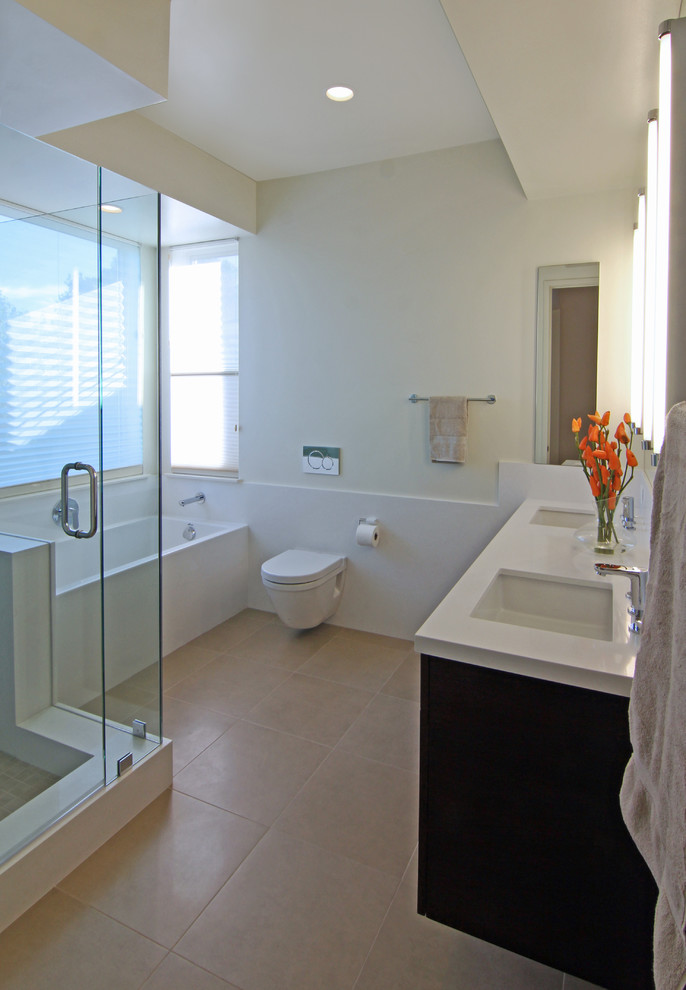 Inspiration for a mid-sized modern master bathroom in San Francisco with an undermount sink, flat-panel cabinets, medium wood cabinets, glass benchtops, an alcove tub, a corner shower, a wall-mount toilet, beige tile, porcelain tile, yellow walls and porcelain floors.