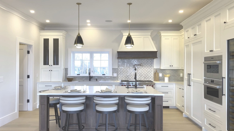 Large transitional l-shaped light wood floor kitchen pantry photo in Boston with an integrated sink, recessed-panel cabinets, white cabinets, quartz countertops, brown backsplash, ceramic backsplash, stainless steel appliances, an island and yellow countertops