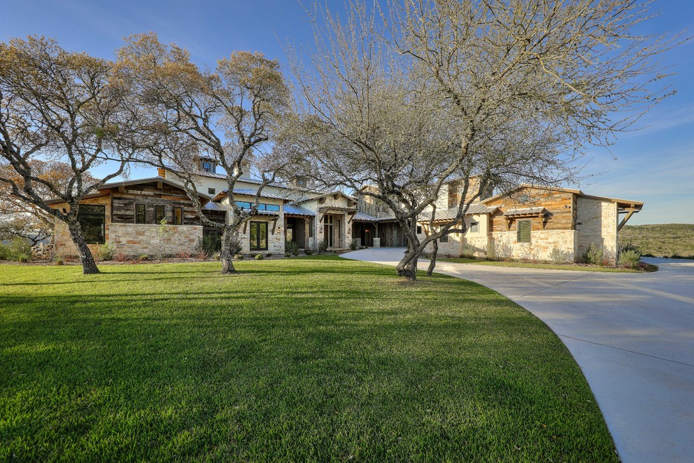 Photo of an expansive country two-storey house exterior in Austin with wood siding and a metal roof.