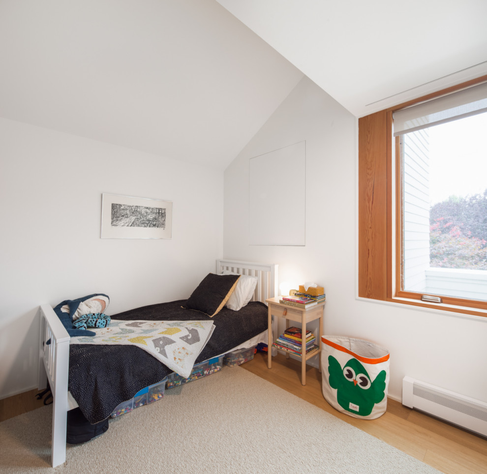 Esempio di una cameretta per bambini da 4 a 10 anni minimalista con pareti bianche e pavimento in legno massello medio