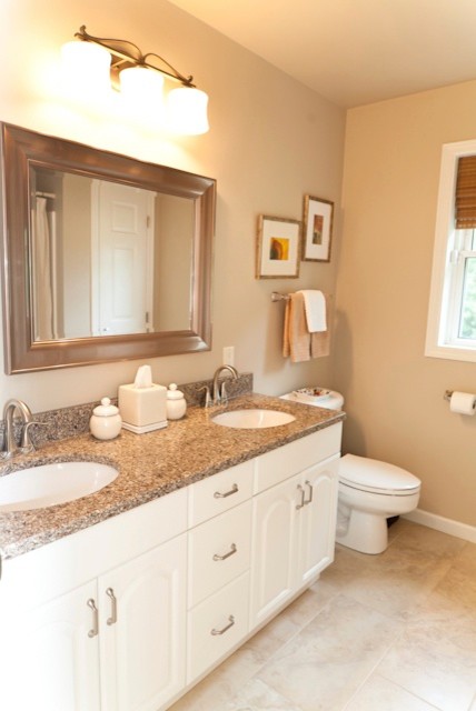 Bathroom - mid-sized transitional beige tile and porcelain tile porcelain tile bathroom idea in Charlotte with an undermount sink, raised-panel cabinets, white cabinets, quartz countertops, a two-piece toilet and beige walls