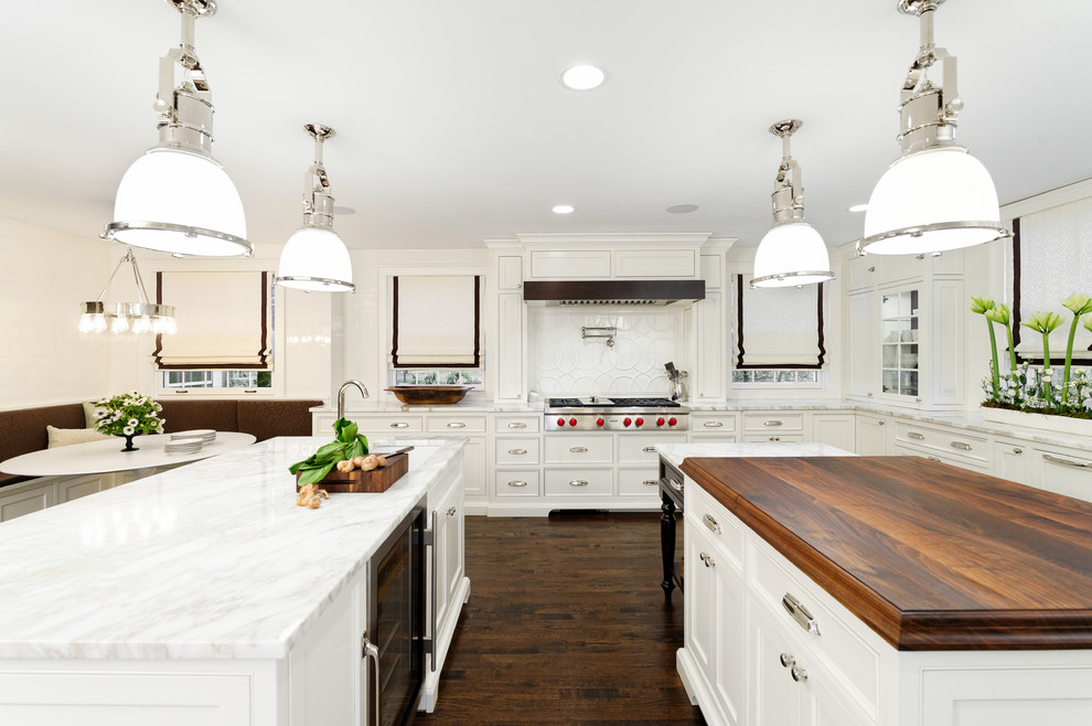 Photo of a large transitional u-shaped eat-in kitchen in Cleveland with an undermount sink, beaded inset cabinets, white cabinets, marble benchtops, white splashback, ceramic splashback, panelled appliances, dark hardwood floors and multiple islands.
