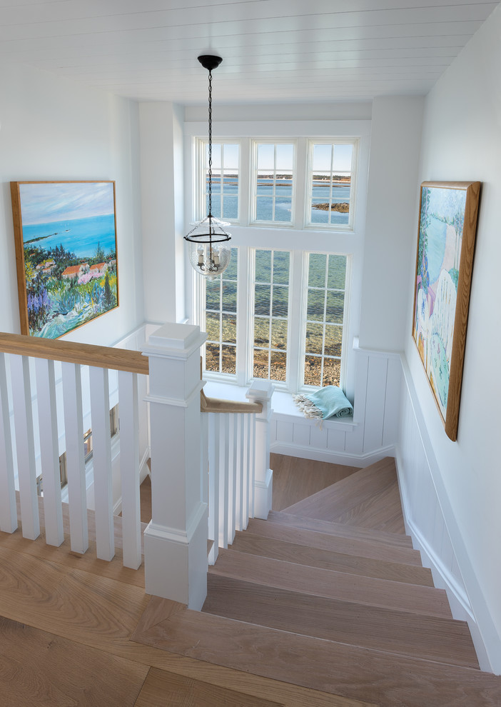 Small beach style wood u-shaped staircase in Portland Maine with painted wood risers and wood railing.