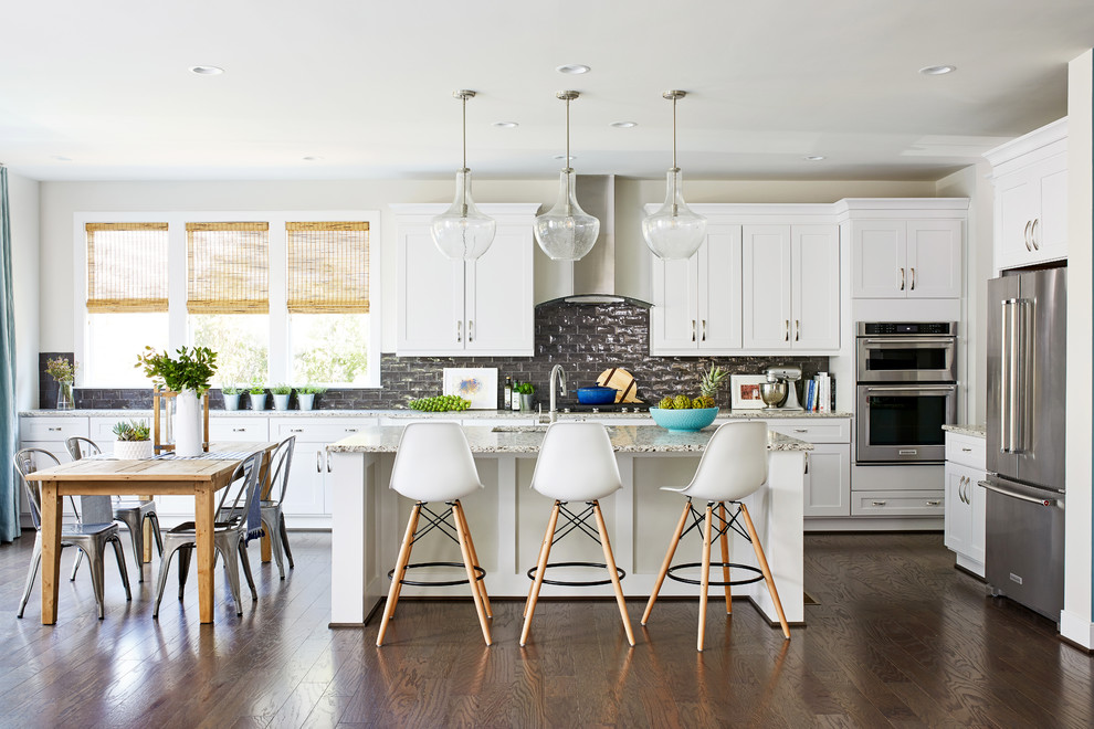 This is an example of a mid-sized transitional l-shaped eat-in kitchen in Boston with shaker cabinets, white cabinets, grey splashback, subway tile splashback, stainless steel appliances, dark hardwood floors, with island, brown floor, beige benchtop and an undermount sink.