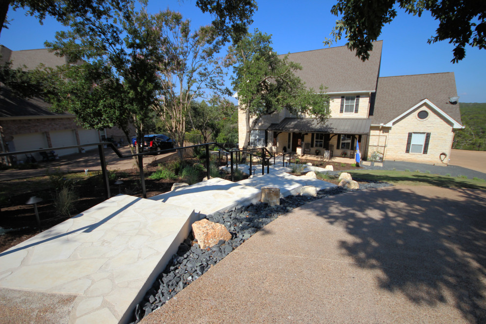 Inspiration for an expansive contemporary front yard shaded driveway in Austin with with path, natural stone pavers and a metal fence.