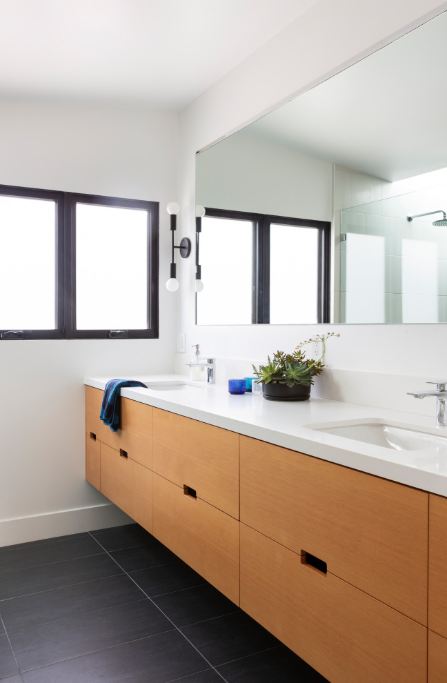 サンフランシスコにある北欧スタイルのおしゃれなマスターバスルーム (フラットパネル扉のキャビネット、淡色木目調キャビネット、白い壁、アンダーカウンター洗面器、白い洗面カウンター、洗面台2つ、フローティング洗面台、グレーの床) の写真