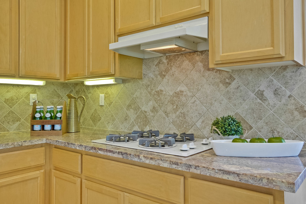 Photo of a traditional l-shaped eat-in kitchen in San Francisco with an undermount sink, raised-panel cabinets, light wood cabinets, granite benchtops, beige splashback, stone slab splashback, stainless steel appliances, cement tiles, a peninsula and beige floor.