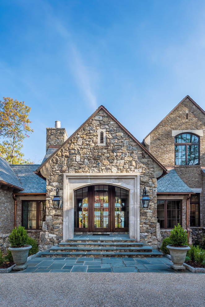Design ideas for an expansive traditional two-storey brown exterior in Other with stone veneer and a gable roof.