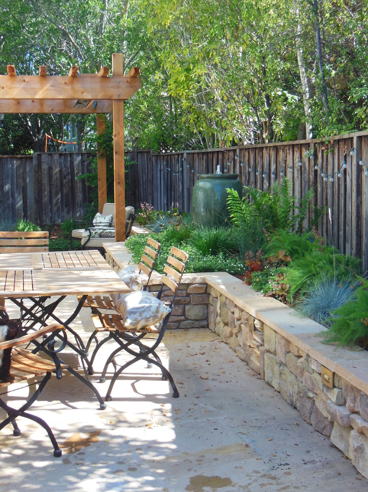 This is an example of a small traditional backyard patio in San Francisco with a water feature, natural stone pavers and a pergola.
