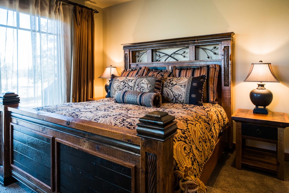 Example of a mid-sized mountain style master carpeted bedroom design with beige walls, a corner fireplace and a stone fireplace