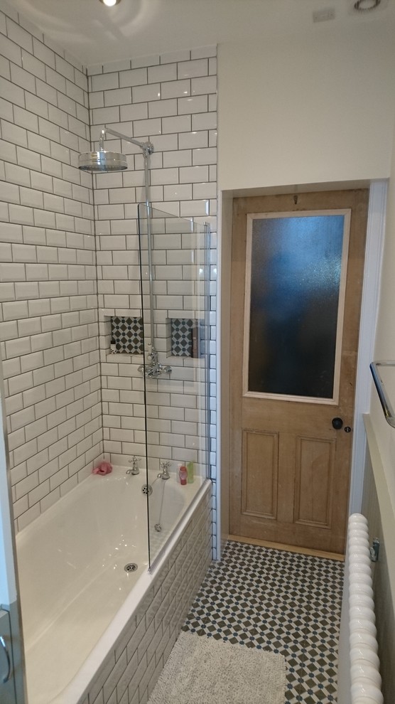 This is an example of a small traditional bathroom in Other with raised-panel cabinets, a drop-in tub, an alcove shower, white tile, subway tile, white walls and ceramic floors.