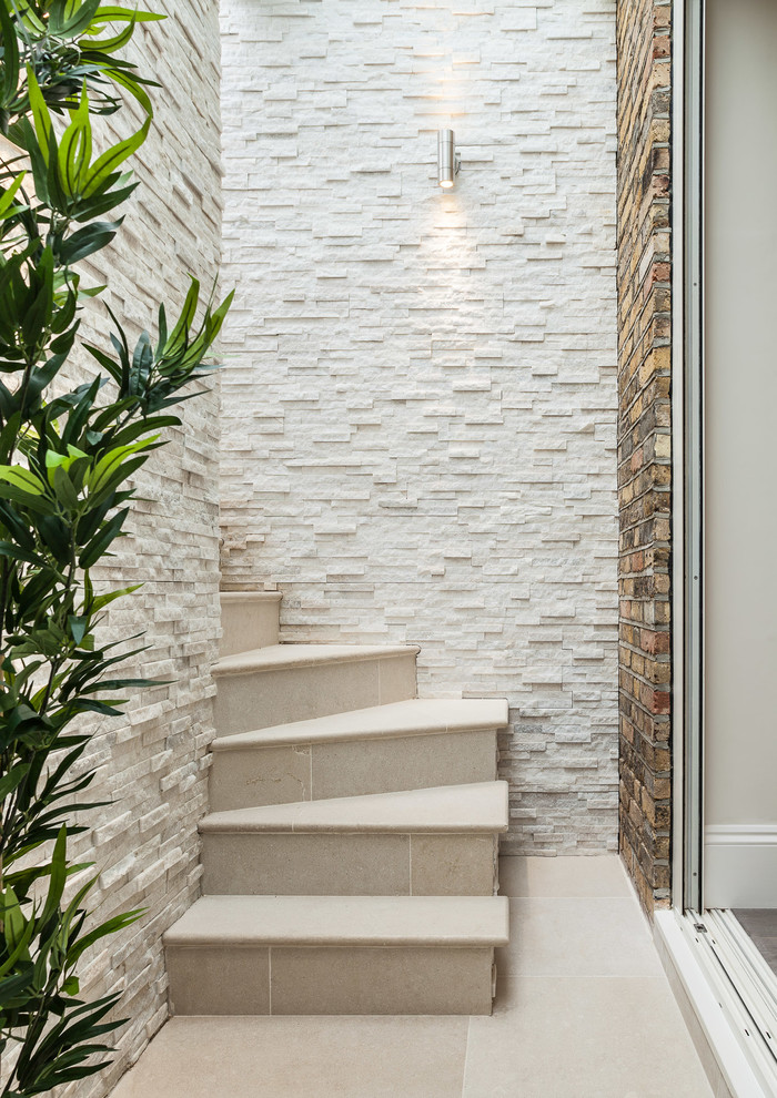 This is an example of a small contemporary curved staircase in London with tile risers.