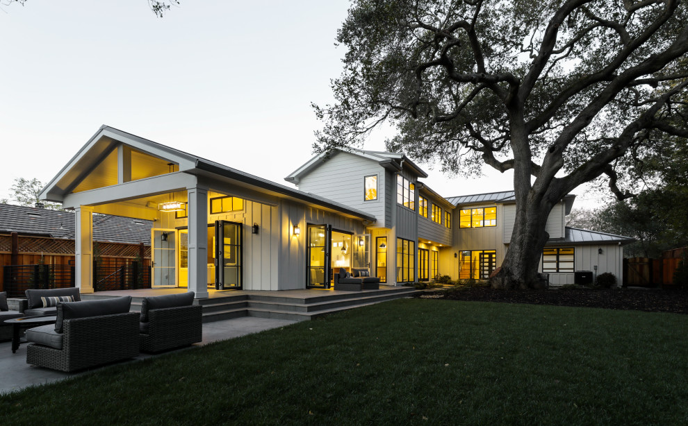 Photo of a country two-storey white house exterior in San Francisco with wood siding, a gable roof and a metal roof.