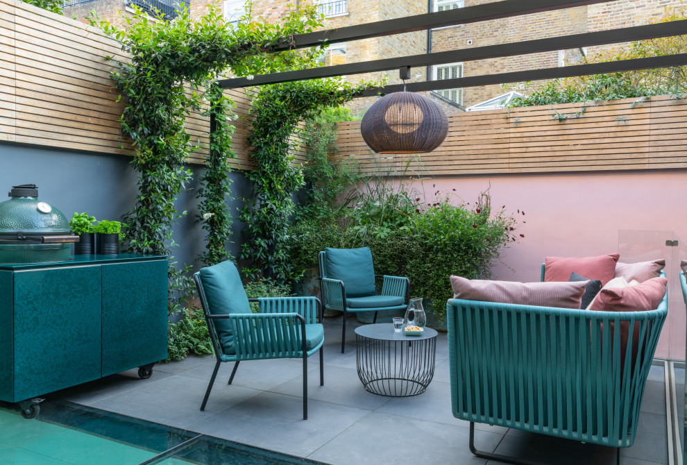 Small contemporary backyard patio in London with tile and a pergola.